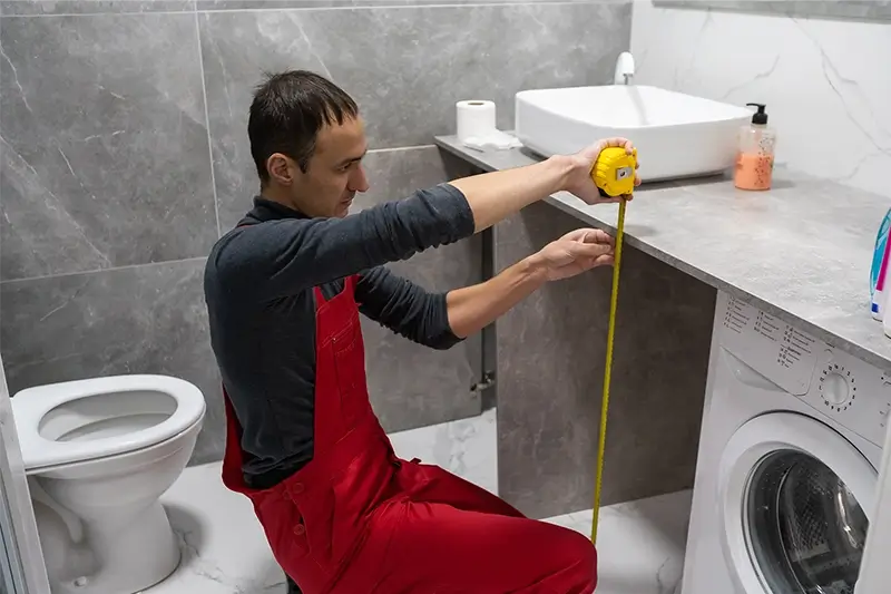 Mężczyzna mierzy szafkę w łazience