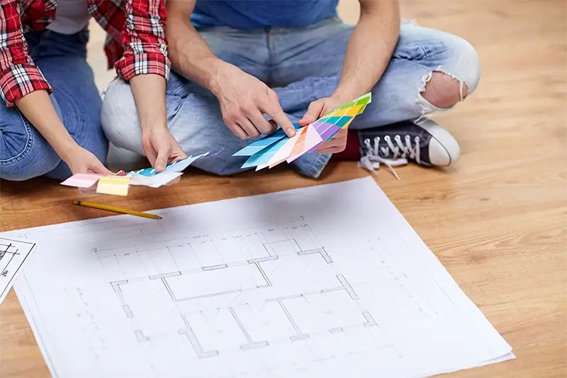 Para z próbkami planu i kolorów siedzących na podłodze w domu