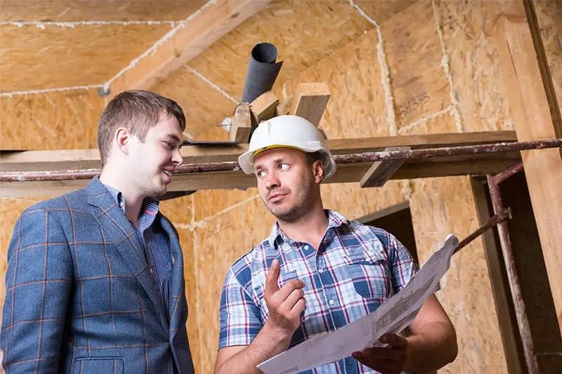 Architekt i majster rozmawiają na poddaszu