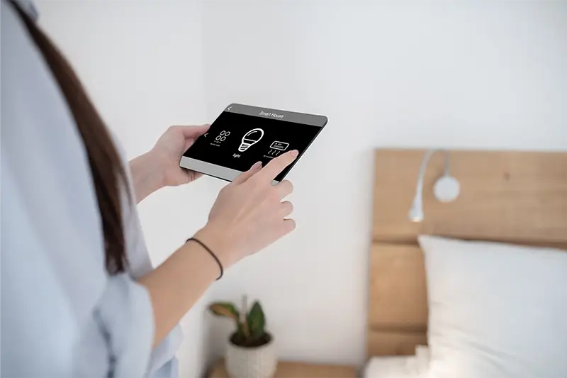 Kobieta włącza światło za pomocą tabletu