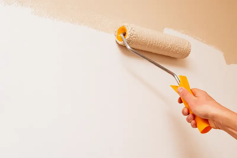 Ręka trzymająca wałek i malującą ścianę