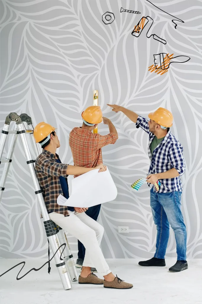 Trzech pracowników w kaskach sprawdzają poziom ściany podczas remontu