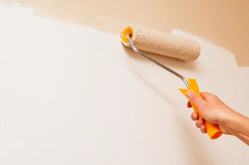 Zrób to sam proste projekty i naprawy, które możesz wykonać samodzielnie - Ręka trzymająca wałek i malującą ścianę